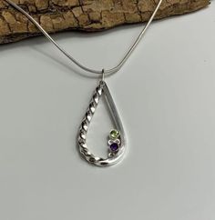 Description Sterling Silver teardrop shape pendant with a twist and beaded decoration and set with natural Amethyst and Peridot . Complete with a sterling silver chain. Handmade at my workshop in Cornwall   Post and Packaging Packaged in a presentation box with organza bag and delivered free within the UK. Dimensions Pendant approximately  4cm x 1.5 ( may vary slightly in size as everything is handcrafted ) Necklace Length Choose from 16 inch (sits close to the neck) or 18 inch (sits mid-chest). Preference varies from person to person. Amethyst And Peridot, Silver Necklace Simple, Pear Shaped Pendant, Amethyst Necklace Pendant, Handmade Bangles, Stacked Bangles, Jewellery Uk, Handcrafted Necklace, Sustainable Jewelry