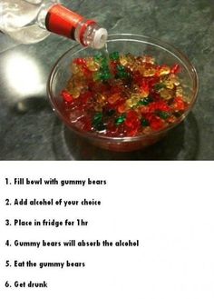 a glass bowl filled with gummy bears next to a bottle