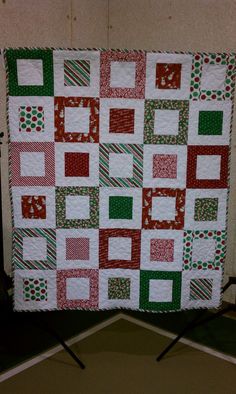 a quilted wall hanging on the side of a building with red and green squares