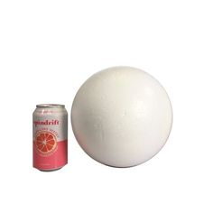 a white ball next to a can of soda