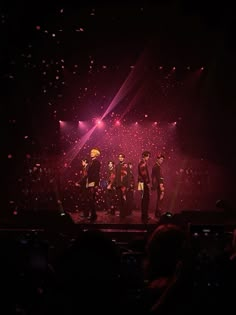 a group of people standing on top of a stage with confetti in the air