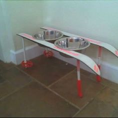 an upside down dog bowl stand with two bowls on it's sides and red wheels