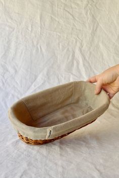 a person is holding a basket on a white sheeted surface with a hand reaching for it