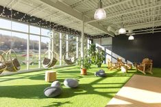 an indoor area with artificial grass and hammocks on the ground in front of large windows