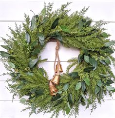 a christmas wreath with bells and greenery on a white wooden background, top view