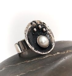 The most stunning and quite unique Silver and Pearl Danish Swedish / modernist / brutalist styled ring. The ring is hallmarked 925 and depicts a bowl or cauldron containing a pearl and smaller silver balls. Very unusual and quite striking and in perfect condition.  The ring is an English size P and a 7.5 US. The pen is just for scale and not included. Please feel free to ask any questions, I'm happy to help, and many thanks for visiting our new Etsy store. Modernist Hand Cast Sterling Silver Rings, Hand Cast Modernist Ring As Gift, Modernist Hand Cast Ring As Gift, Oxidized Finish Oval Rings For Anniversary, Hand Cast Modernist Ring, Oval Rings With Oxidized Finish For Anniversary, Modernist Silver Ring With Oxidized Finish, Hand Forged Sterling Silver Modernist Rings, Modernist Oxidized Silver Ring