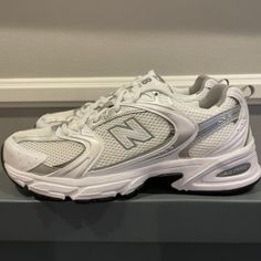 the new balance 990 running shoe is white and grey with silver accents on the upper part