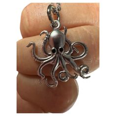 an octopus shaped pendant is being held in someone's hand