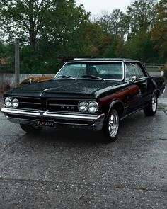 an old black car parked in a parking lot