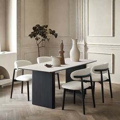 a dining room table with chairs and vases on it