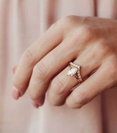 a woman's hand wearing a gold ring with an oval shaped diamond on it