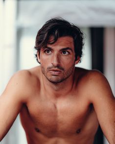 a shirtless man with no shirt on is looking at the camera while sitting down