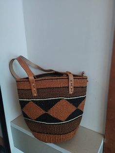 Geometrical earth tone sisal tote bag. Unique and stylish colorful sisal kiondo bag with stitched leather straps, pocket lining and zipper. Patterns and sizes slightly vary because weaving and stiching is done by hand. Ideal as a beach bag, shopping basket, market basket or storage basket. This unique tote bag is handmade by a group of ladies in a remote rural village in Machakos, Kenya. Do not clean with brush or water. If the bag gets wet, please dry to avoid dampness.  Leather type used is bo Brown Box Bag With Handles For Shopping, Natural Beach Bag With Removable Pouch And Double Handle, Brown Bucket Bag For Daily Use, Brown Handheld Bucket Bag For Daily Use, Natural Tote Beach Bag With Removable Pouch, Natural Color Tote Beach Bag With Removable Pouch, Brown Handheld Bag With Top Carry Handle, Brown Satchel Box Bag With Handles, Brown Bucket Bag With Double Top Handle