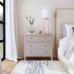 a bedroom with a bed, dresser and large window in the corner next to it