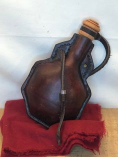 an old wooden jug sitting on top of a red cloth next to a white wall