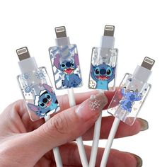 the person is holding four small toothbrushes with cartoon characters on them in their hands