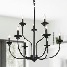 a black chandelier with six lights hanging from it's center, in a white room