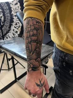 a man's arm with a ship tattoo on it