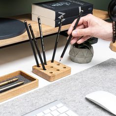 a person is holding some pencils in front of a computer keyboard and mouse on a desk