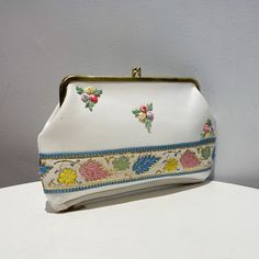 Vintage 60s White Vinyl Floral Embroidered Kiss Lock Clutch/Purse, Cosmetics Bag. This Purse Was Never Used. White Vinyl With Embroidered Floral,Pink, Blue, Yellow, Green And Red, On Front. Floral Embroidered Ribbon With Gold Accents Along Bottom Front. Deep Zippered Compartment On Bottom. Green, And Tan Floral Lined. Interior Is Lined With Green Vinyl. Gold Tone Frame And Kiss Lock. Tag From Sale Left A Tiny Hole On Side Front, Gold Tone Frame Has Some Fading (See Pics) Otherwise, No Flaws, Cle Compact White Bag For Daily Use, White Retro Handheld Bag, Vintage White Pouch Shoulder Bag, Vintage White Embroidered Bags, Vintage White Rectangular Bag, Vintage White Handheld Shoulder Bag, White Vintage Rectangular Bag, White Rectangular Vintage Bag, Vintage White Pouch Bag