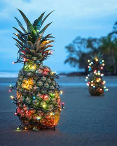 two pineapples decorated with lights on the beach