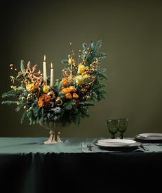 an arrangement of flowers in a vase on a table with two plates and silverware