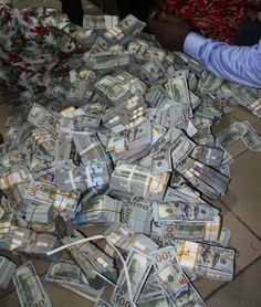 a pile of money sitting on top of a floor next to a man in a blue shirt