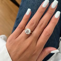 a woman's hand with white manicured nails and a diamond ring