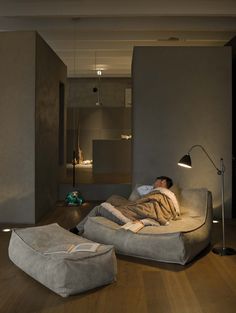 a man laying on top of a couch in a living room next to a lamp