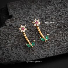 pair of gold plated earrings with green and white stones on black stone flooring