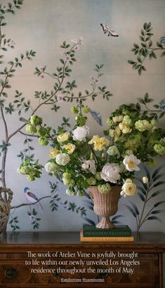 a vase filled with flowers sitting on top of a wooden table next to a wall