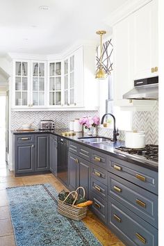 a kitchen with black and white cabinets, gold trimmings and an area rug on the floor