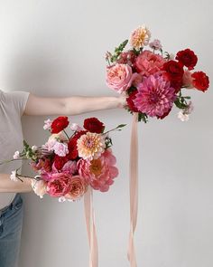 a woman is holding a bunch of flowers in her hand and the other one has a bouquet on it