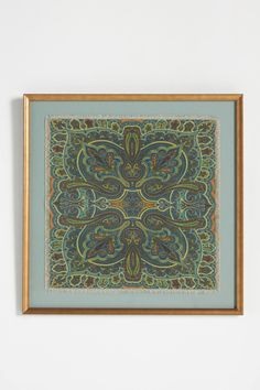 a painting hanging on the wall with a wooden frame in front of it that has a blue and green paisley design