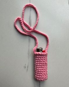 a pink crocheted cell phone case with a lanyard hanging from it's side