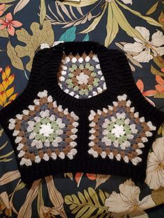 a crocheted black vest with flowers on it