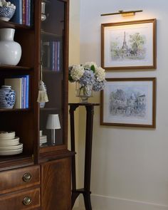 a vase with flowers sitting on top of a table next to a book shelf filled with books