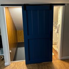 an open blue door in a room with hardwood floors and white walls, leading to a closet