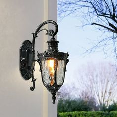 an old fashioned wall light on the side of a building with trees in the background