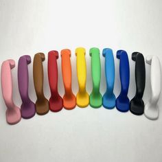 a row of different colored plastic utensils on a white surface