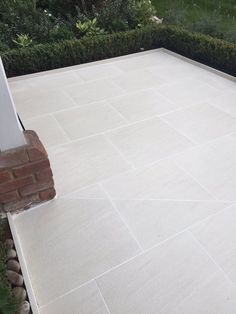 an empty patio in the middle of a garden with hedges and bushes around it,