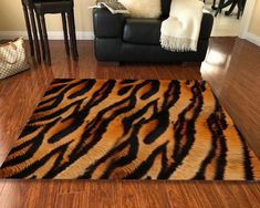 a living room with a couch, chair and tiger print rug on the hardwood floor