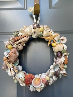 a wreath made out of seashells hangs on the front door