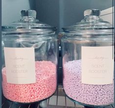 two large glass jars filled with pink and purple candies sitting on top of a metal rack