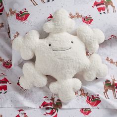 a white stuffed animal laying on top of a bed covered in santa claus print sheets