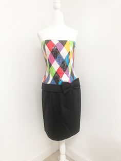 This is a strapless dress from Jenna Benjamin, USA. The bodice of the dress is a colorful harlequin pattern that is completely covered in clear sequins, giving it a lovely shine. The skirt is solid black and the low waist is accented with a bow. The dress zips in the back and is boned in the bodice. Size tag 6. Check measurements carefully, no stretch. Measurements taken with dress laying flat and doubled where appropriate. In order to determine fit we recommend comparing measurements with an it Elegant Multicolor Strapless Evening Dress, Retro Multicolor Mini Dress For Party, Elegant Multicolor Strapless Dress, Elegant Fitted Multicolor Strapless Dress, Multicolor Strapless Dress For Party Season, Multicolor Strapless Dress For Night Out, Multicolor Mini Strapless Dress For Party, Multicolor Strapless Fitted Mini Dress, Multicolor Fitted Strapless Mini Dress