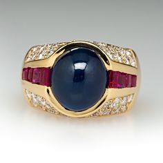 This exquisite ring is centered with an oval, sapphire cabochon in a partial bezel setting. The shoulders are each channel set with four (4) square mixed cut rubies. The top of the ring is bead set with a total of forty-six (46) round brilliant cut diamonds. The ring measures 13.7mm at the top, rises 11.2mm above the finger, tapering to 5.5mm wide and 1.3mm thick at the base of the shank. This ring is currently a size 7. Formal Oval Cabochon Sapphire Ring, Classic Cabochon Sapphire Ring For Formal Occasions, Classic Formal Cabochon Sapphire Ring, Luxury Multi-stone Cabochons For Formal Occasions, Classic Formal Sapphire Cabochon Ring, Formal Polished Finish Oval Cabochon Sapphire Ring, Luxury Sapphire Cabochon Ring, Elegant Sapphire Cabochon Rings, Elegant Cabochon Sapphire Ring