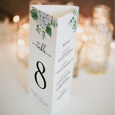 the table numbers are placed on top of the folded menu card for an elegant wedding