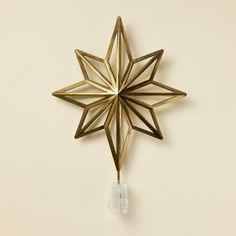 a gold metal star ornament hanging on a wall with clear glass bead beads