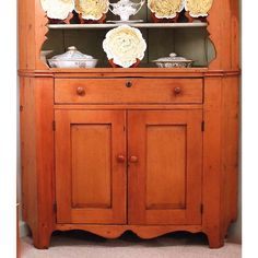 an old fashioned china cabinet with flowers on top